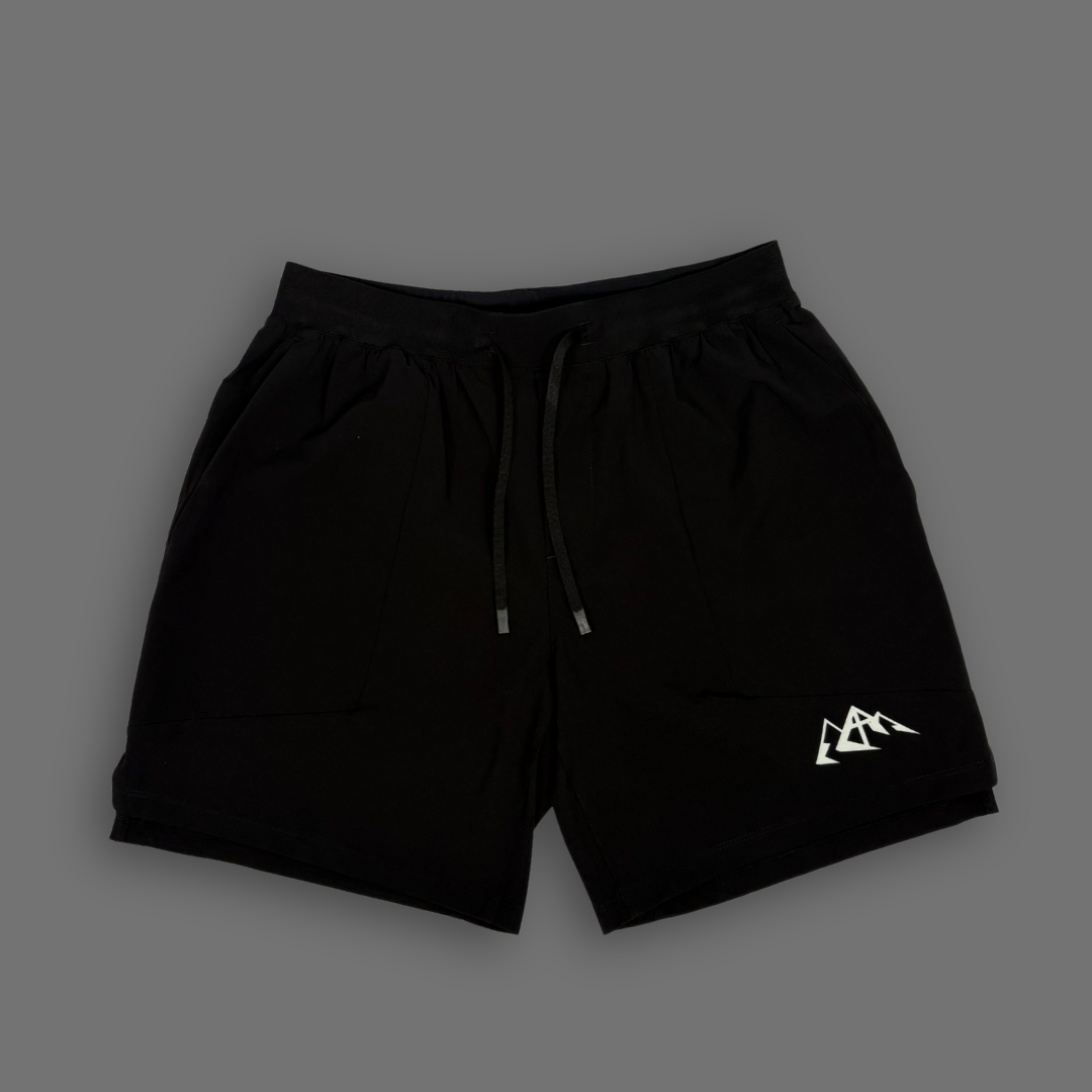 Black athletic shorts with a drawstring waist and a small white mountain logo on the lower left leg, shown against a solid dark gray background.