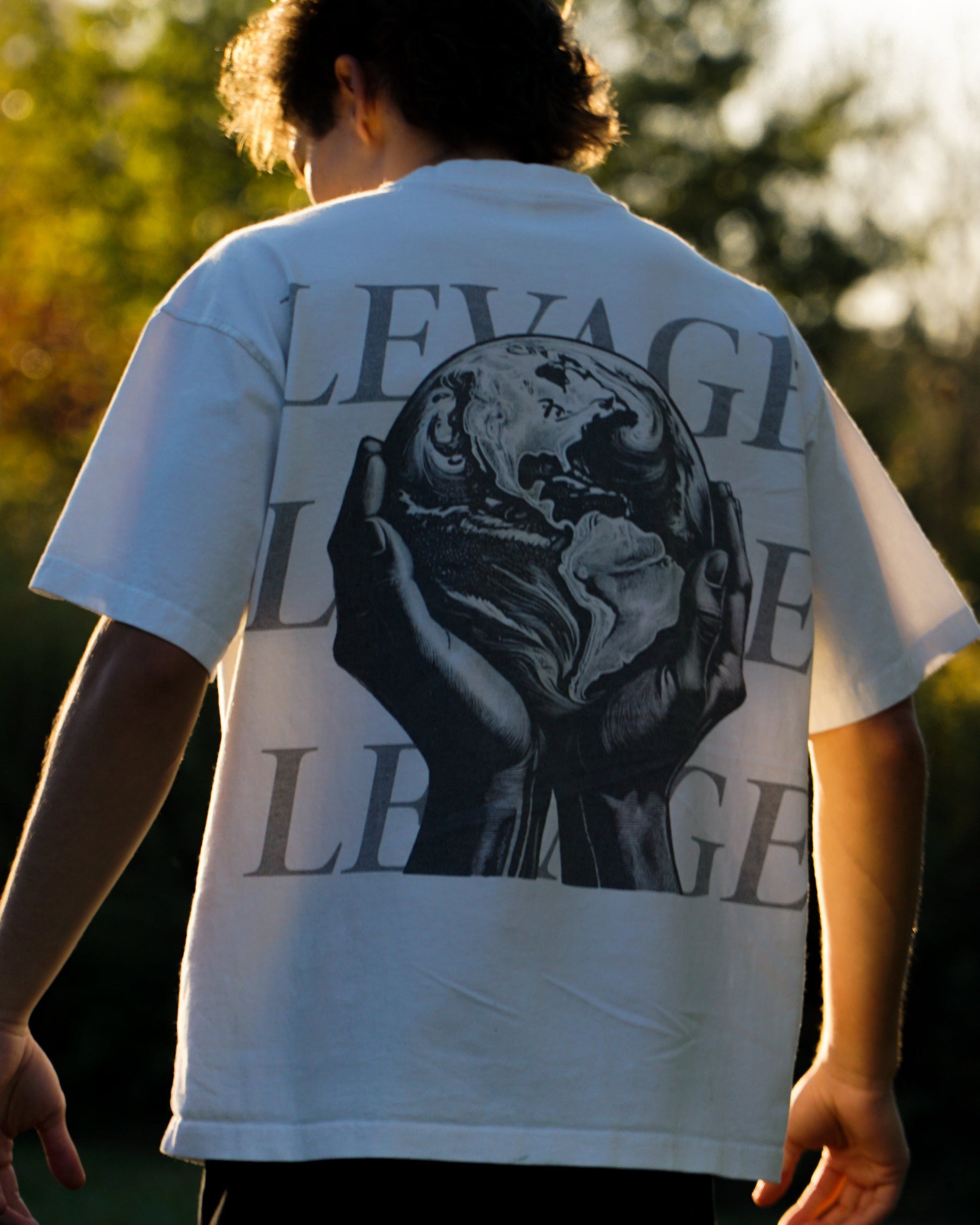 Person wearing a white t-shirt with a graphic design and text outdoors