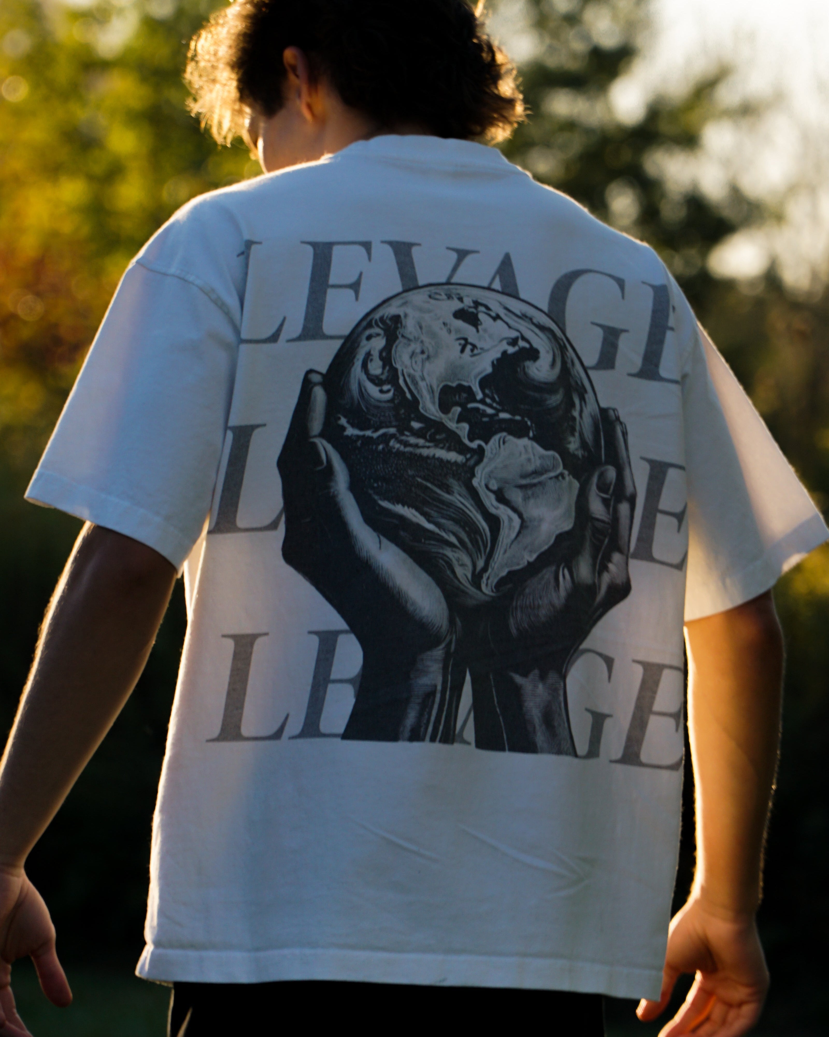 Person wearing a white t-shirt with a graphic design and text outdoors