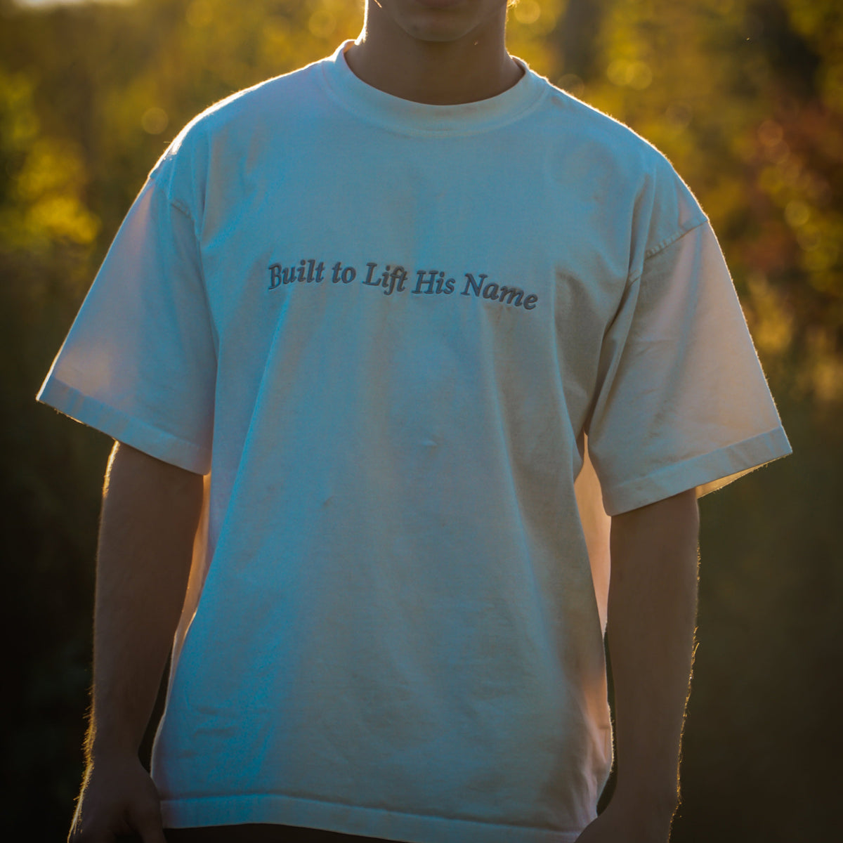 Person wearing a white t-shirt with text in a natural setting