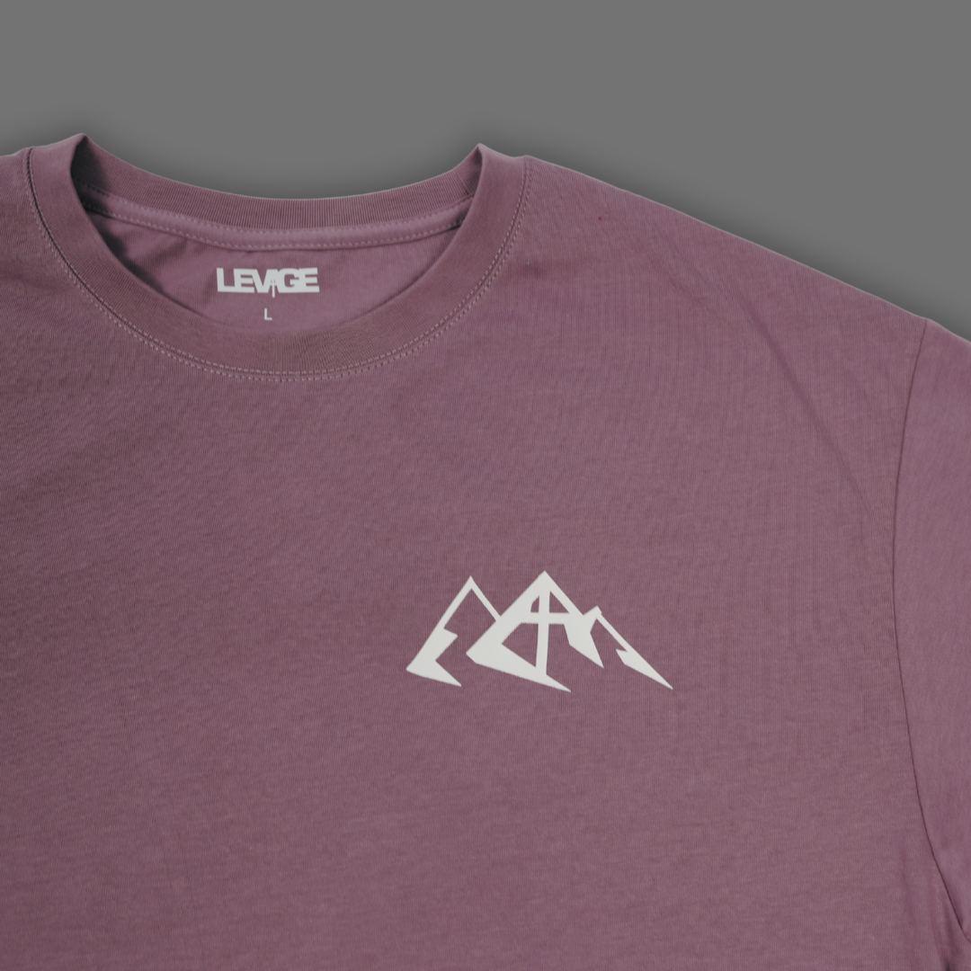 English Lavender short-sleeve crewneck t-shirt by LEVAGE, featuring a white geometric mountain logo on the center chest and a white hangtag with the brand name.