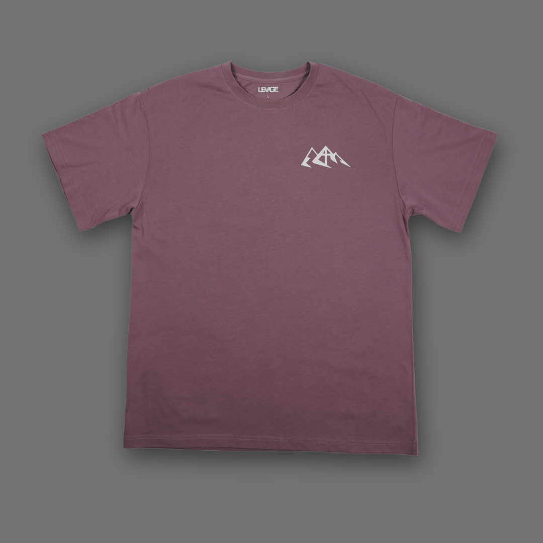 An English lavender short-sleeve crewneck t-shirt with a small white mountain graphic on the left chest, displayed flat against a solid dark gray background.